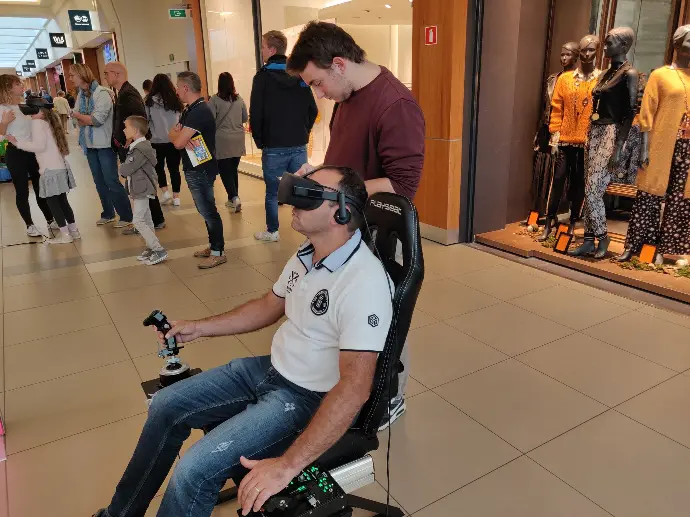 Participant en pleine session sur simulateur de vol avec casque de réalité virtuelle lors d’un événement