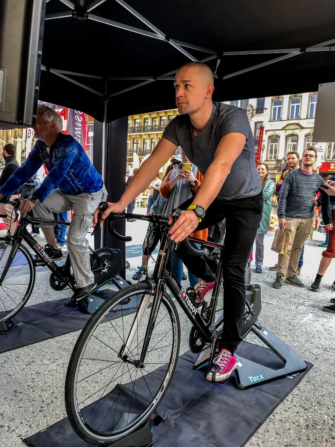 Participant pédalant sur simulateur de vélo connecté avec écran de course